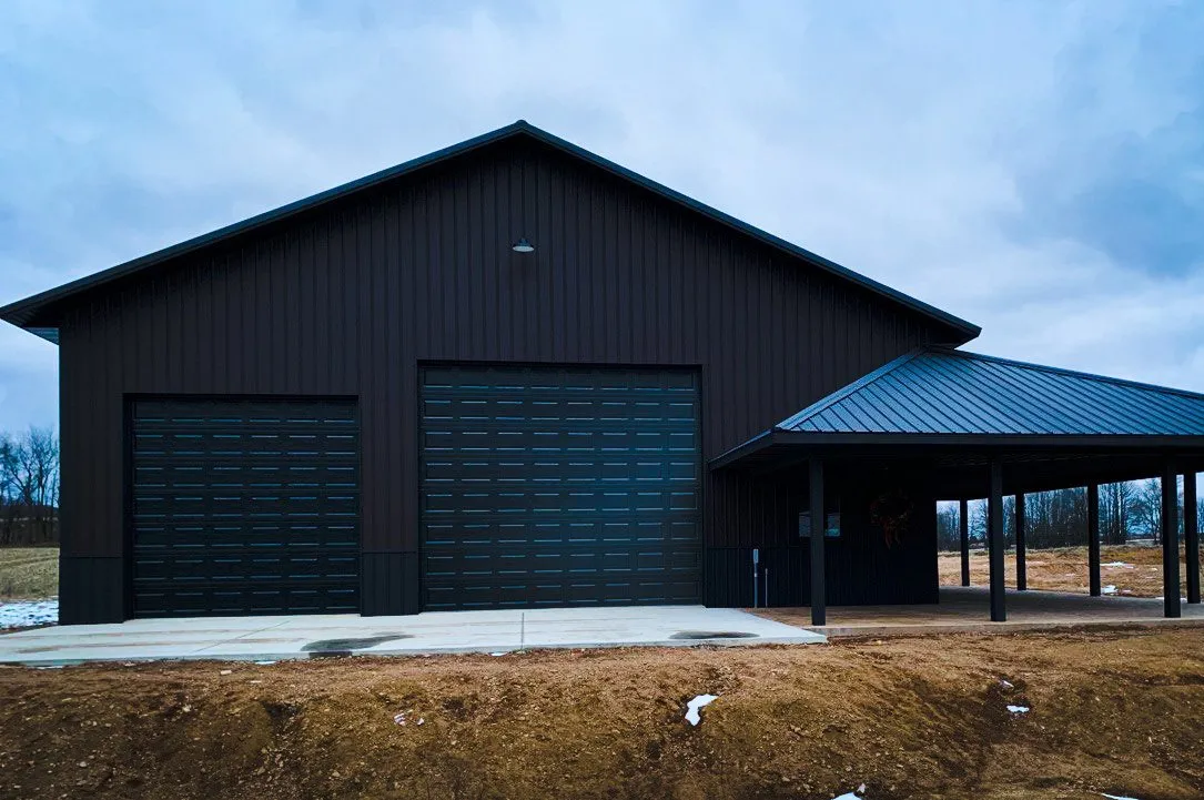 Modern Black Metal Garage with Attached Porch A contemporary black metal garage building featuring dual garage doors and an extended covered porch area with metal supports.